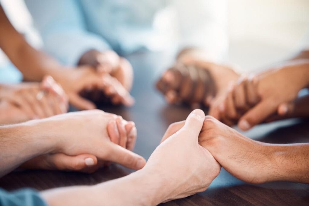 a group of people sit at table and hold each others hands